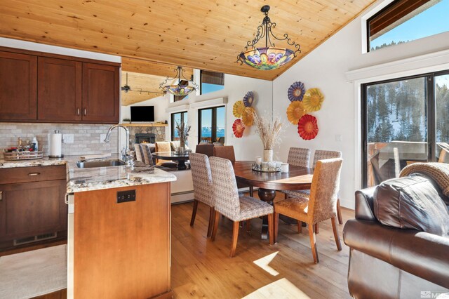 kitchen featuring vaulted ceiling, light stone counters, sink, decorative light fixtures, and backsplash