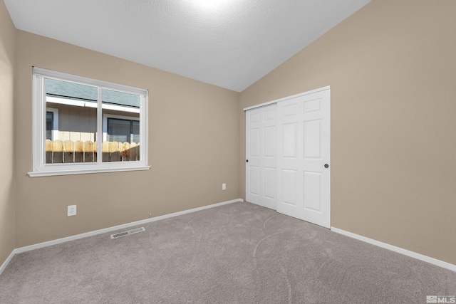 unfurnished bedroom featuring vaulted ceiling, a closet, and light carpet