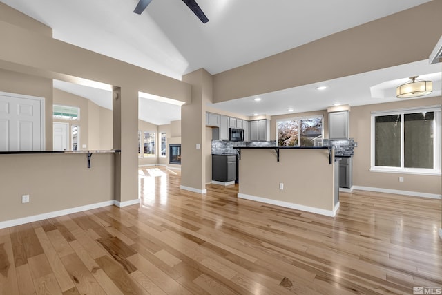 interior space with ceiling fan, vaulted ceiling, and light hardwood / wood-style flooring