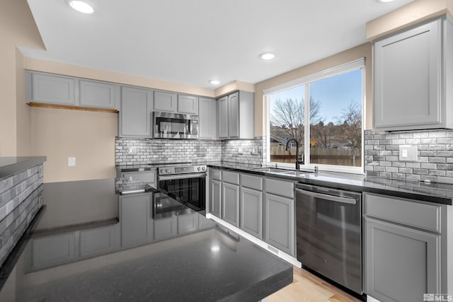 kitchen with light hardwood / wood-style flooring, gray cabinets, backsplash, appliances with stainless steel finishes, and sink