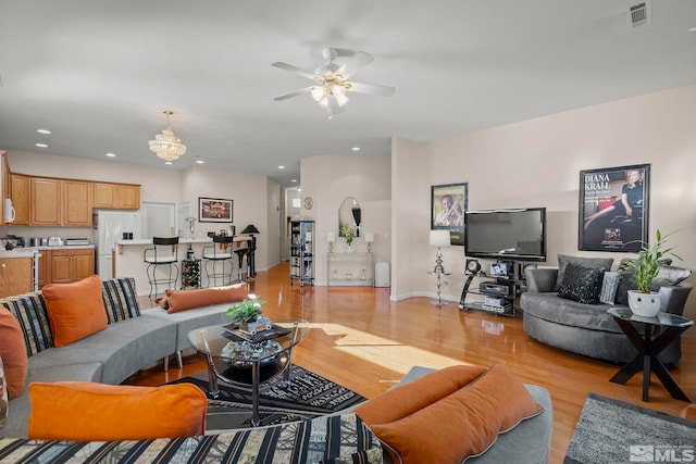 living room with light hardwood / wood-style flooring and ceiling fan with notable chandelier