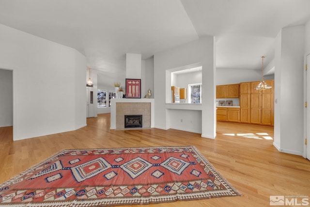 living room featuring a notable chandelier, light hardwood / wood-style flooring, lofted ceiling, and a fireplace