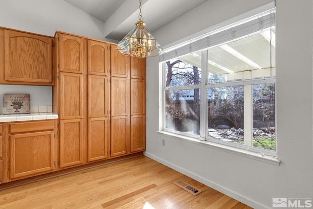 unfurnished dining area featuring light hardwood / wood-style flooring and a chandelier