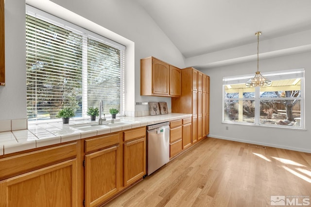 kitchen featuring sink, dishwasher, tile counters, pendant lighting, and a notable chandelier