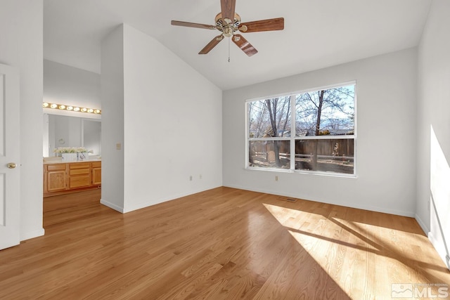 interior space with ceiling fan, light hardwood / wood-style floors, ensuite bathroom, and vaulted ceiling