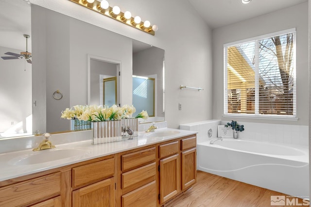 bathroom featuring independent shower and bath, ceiling fan, wood-type flooring, and vanity