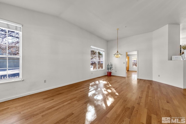 unfurnished dining area featuring light wood-type flooring, an inviting chandelier, and lofted ceiling