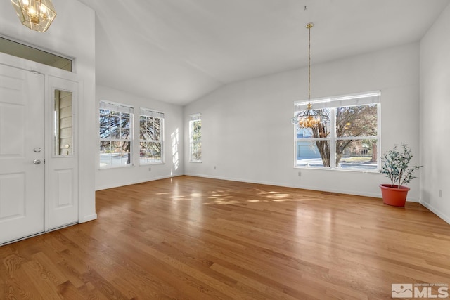 unfurnished dining area with wood-type flooring, a chandelier, and vaulted ceiling