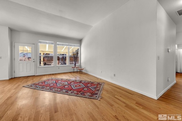 unfurnished living room featuring lofted ceiling and hardwood / wood-style flooring