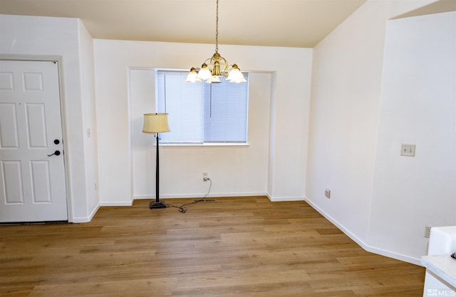 unfurnished dining area with a chandelier and light wood-type flooring