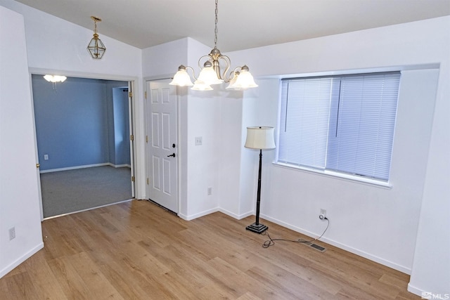 unfurnished room with hardwood / wood-style flooring, vaulted ceiling, and a chandelier