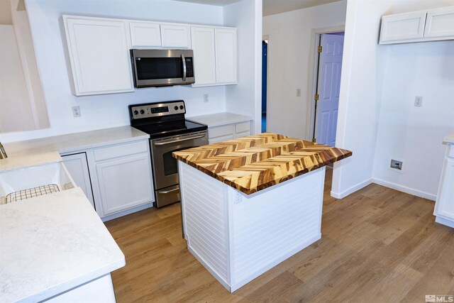 kitchen featuring stainless steel appliances, a kitchen island, light wood-type flooring, white cabinetry, and sink