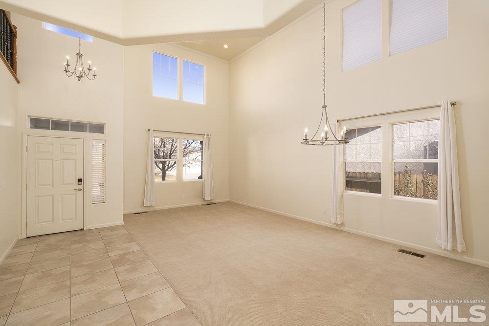 carpeted foyer entrance featuring a high ceiling and an inviting chandelier