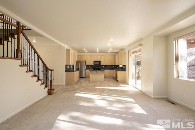 interior space featuring light brown cabinets, plenty of natural light, stainless steel fridge with ice dispenser, and light colored carpet