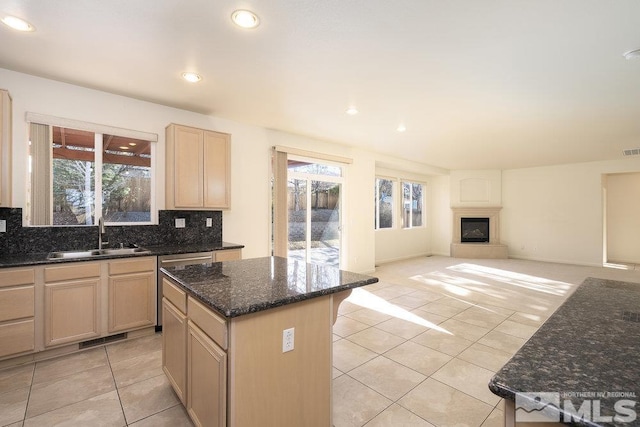 kitchen with sink, a center island, a large fireplace, and light brown cabinets