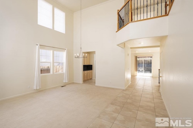 unfurnished living room featuring a towering ceiling, light tile patterned flooring, and a chandelier