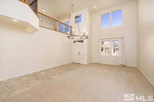 unfurnished living room with a towering ceiling, an inviting chandelier, and light tile patterned flooring