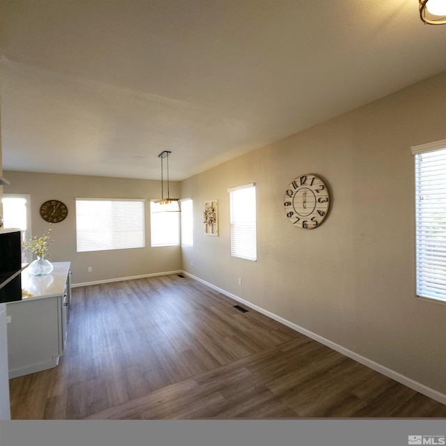 unfurnished dining area featuring dark hardwood / wood-style flooring and a wealth of natural light