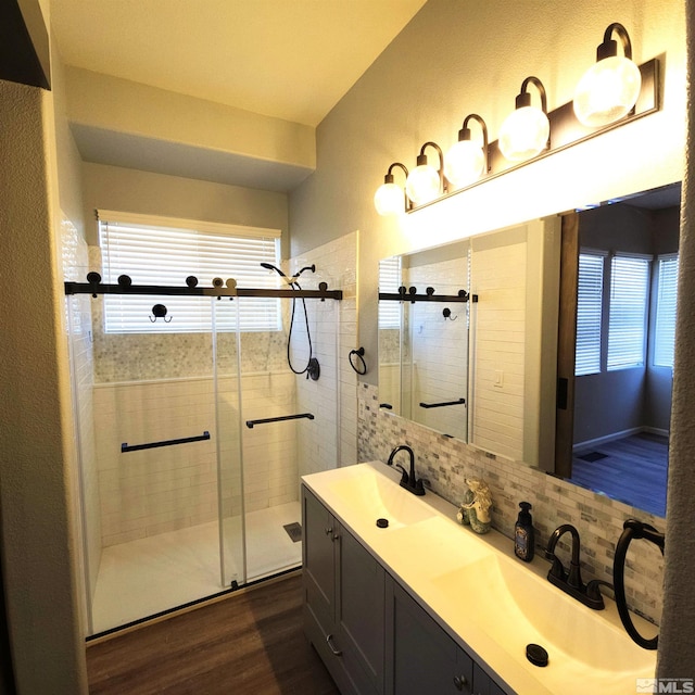 bathroom with hardwood / wood-style flooring, a shower with door, tasteful backsplash, and vanity