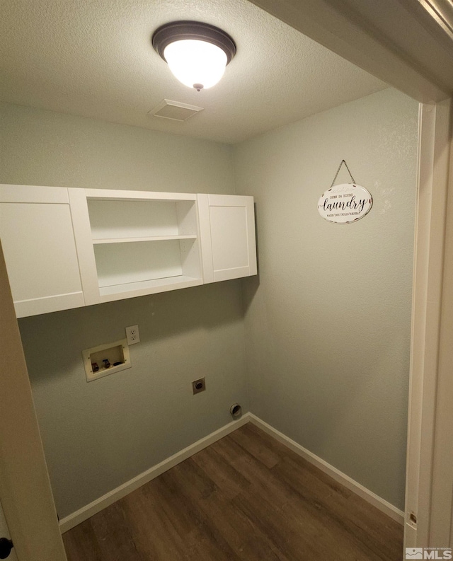 washroom featuring a textured ceiling, hookup for an electric dryer, hookup for a washing machine, cabinets, and dark hardwood / wood-style flooring