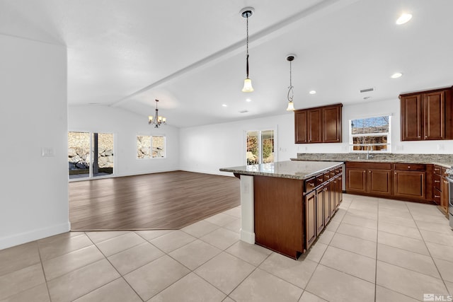 kitchen featuring hanging light fixtures, a center island, light stone counters, and light tile patterned floors