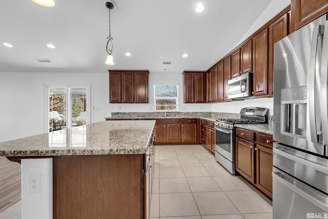 kitchen with sink, appliances with stainless steel finishes, pendant lighting, and a center island