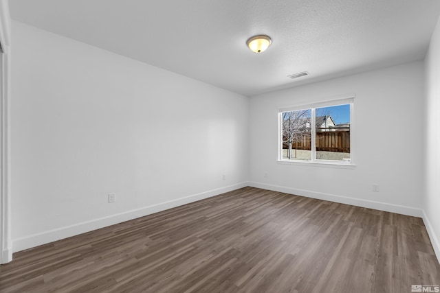 spare room with a textured ceiling and dark hardwood / wood-style floors