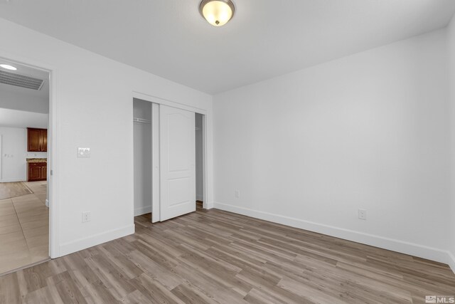 unfurnished bedroom featuring light hardwood / wood-style floors and a closet