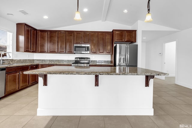 kitchen featuring stainless steel appliances, a kitchen bar, hanging light fixtures, and a center island