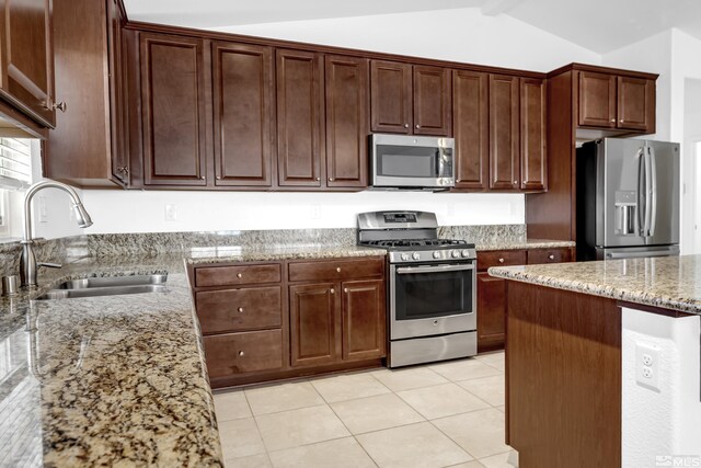 kitchen with appliances with stainless steel finishes, lofted ceiling with beams, light tile patterned floors, light stone counters, and sink