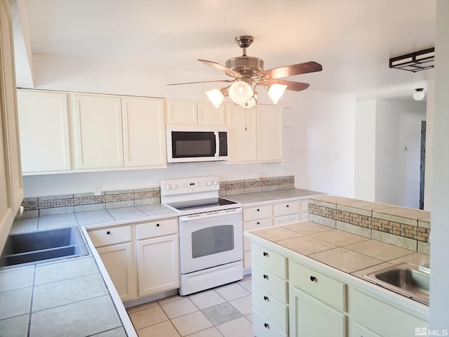 kitchen with sink, white cabinetry, tile countertops, white appliances, and light tile patterned floors