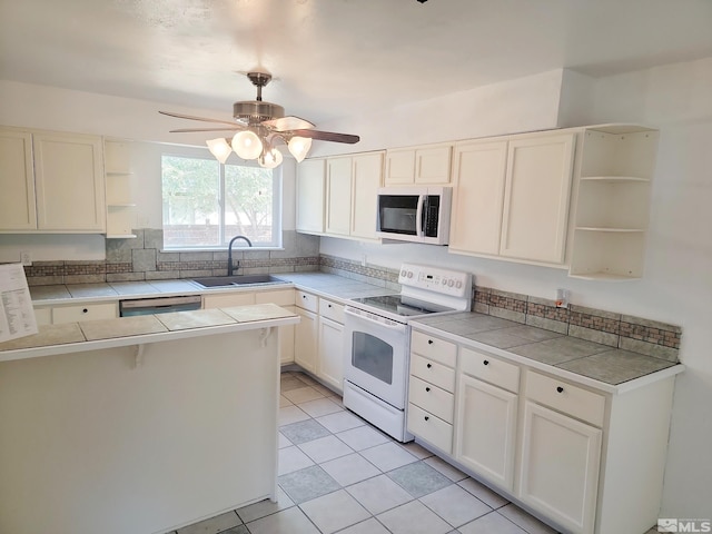 kitchen with white appliances, light tile patterned floors, tile countertops, sink, and white cabinetry