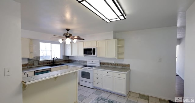 kitchen featuring white appliances, kitchen peninsula, tile countertops, white cabinetry, and sink