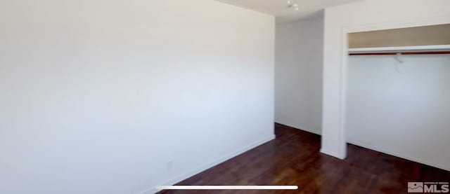 unfurnished bedroom featuring dark hardwood / wood-style flooring and a closet