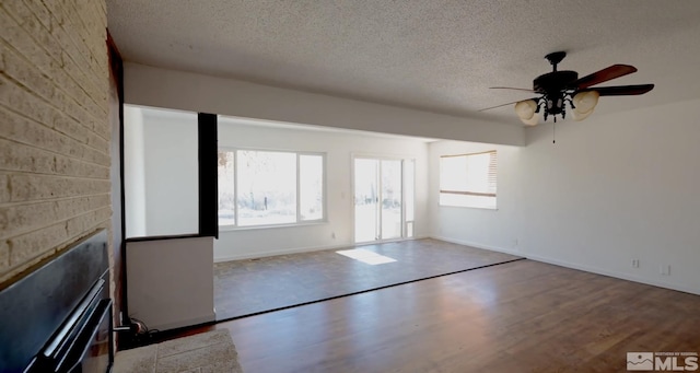 spare room with a fireplace, a textured ceiling, ceiling fan, and light hardwood / wood-style floors