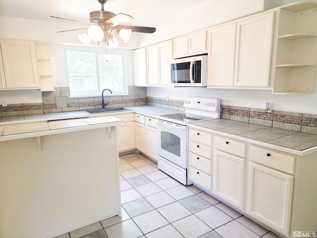 kitchen with white appliances, white cabinetry, sink, and tile counters