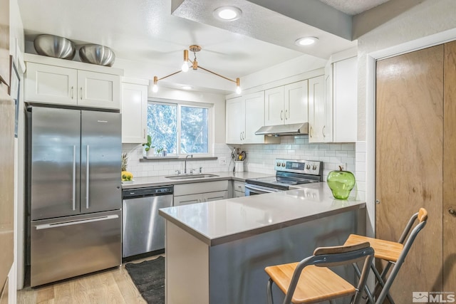 kitchen with kitchen peninsula, stainless steel appliances, white cabinets, and a kitchen bar