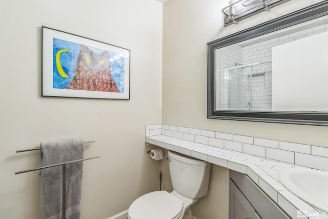 bathroom with toilet, vanity, and a shower with shower door