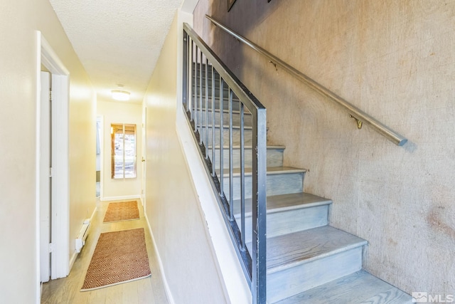 stairway featuring a textured ceiling and wood-type flooring