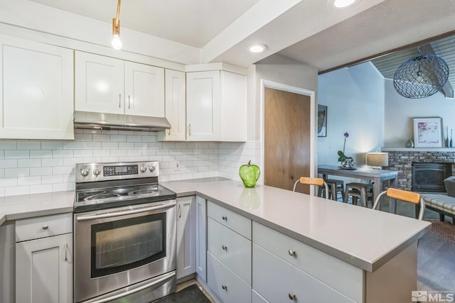 kitchen with kitchen peninsula, pendant lighting, tasteful backsplash, white cabinets, and stainless steel electric range oven