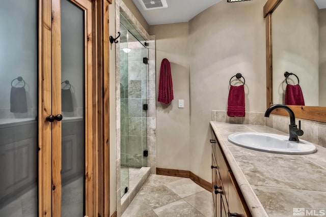 bathroom featuring a shower with shower door and vanity