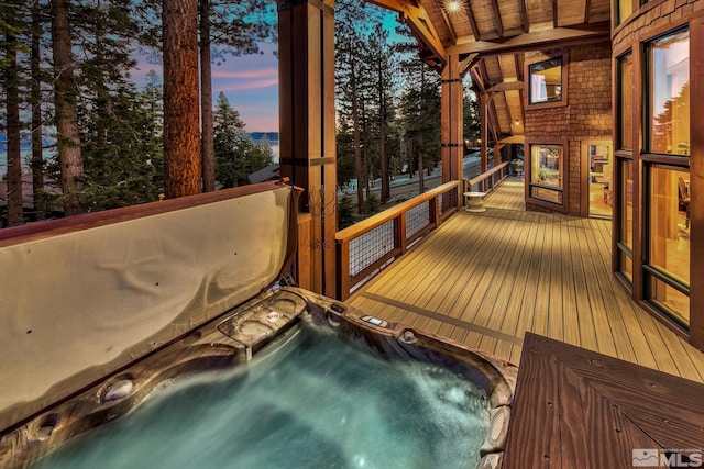 deck at dusk featuring an outdoor hot tub