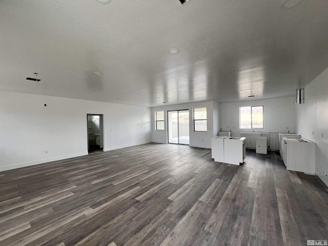 unfurnished living room with a textured ceiling and dark hardwood / wood-style floors