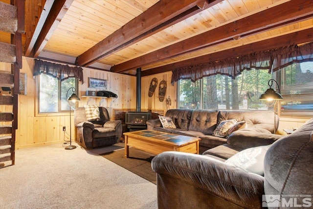 living room featuring plenty of natural light, wood walls, a wood stove, and beamed ceiling