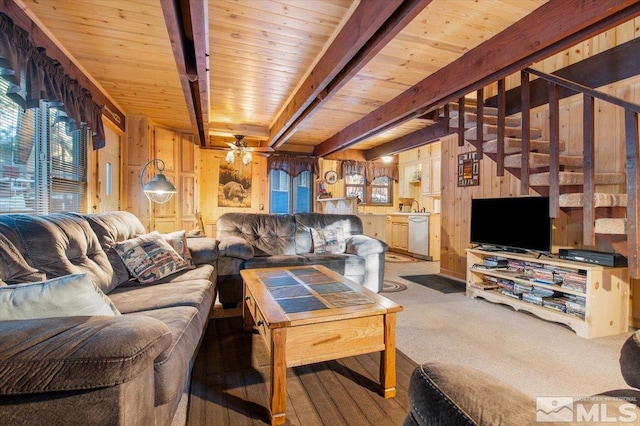 carpeted living room featuring wood walls, ceiling fan, wood ceiling, and beamed ceiling