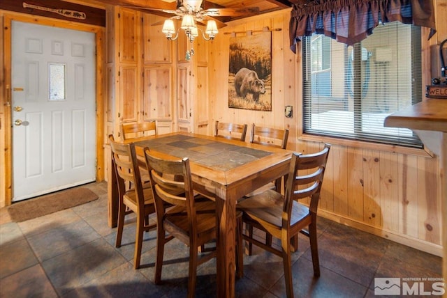 dining area featuring wood walls, ceiling fan, and a wealth of natural light