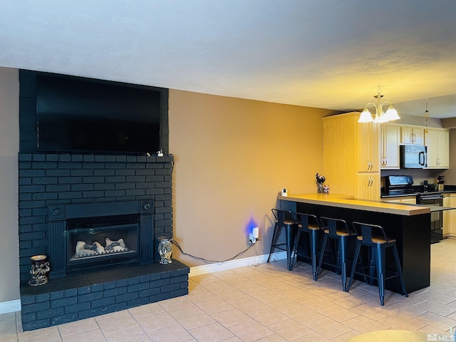 kitchen featuring kitchen peninsula, pendant lighting, black appliances, a breakfast bar area, and a fireplace