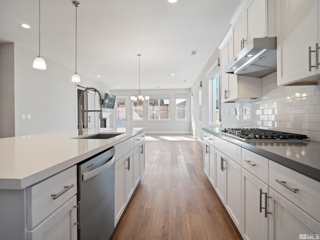 kitchen featuring hanging light fixtures, a large island, white cabinets, appliances with stainless steel finishes, and sink