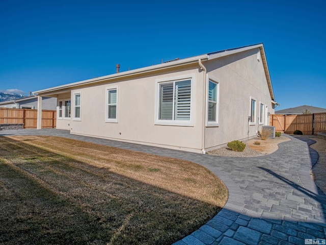 rear view of property with a patio, central AC, and a lawn