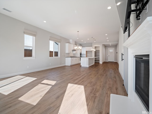 unfurnished living room with a notable chandelier and light hardwood / wood-style flooring